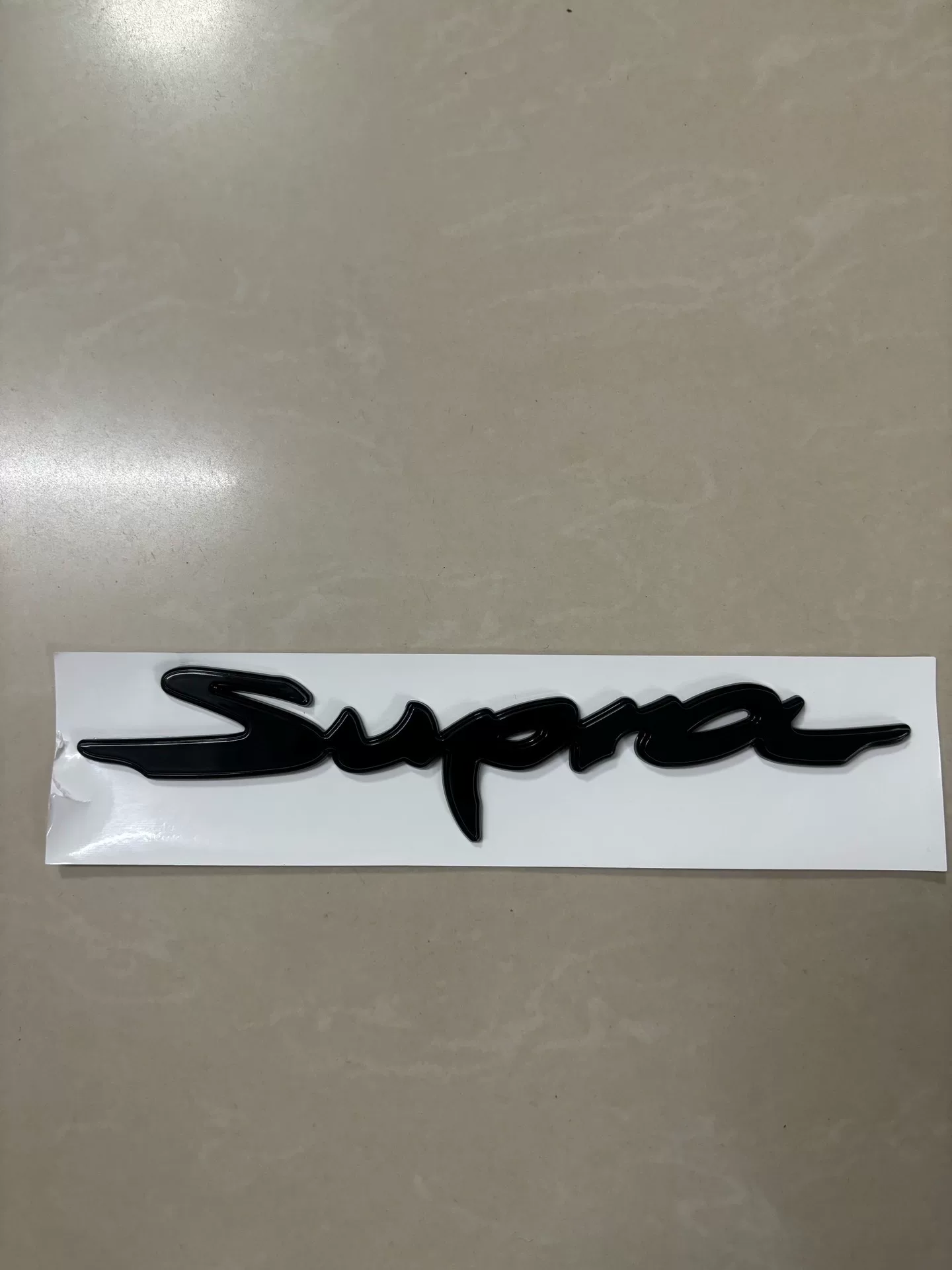 Toyota A90, A91 Used OEM Emblem Badge matte black, red accent A90 Toyota A90, A91 Used OEM Emblem Badge matte black, red accent A90 - detail image 3