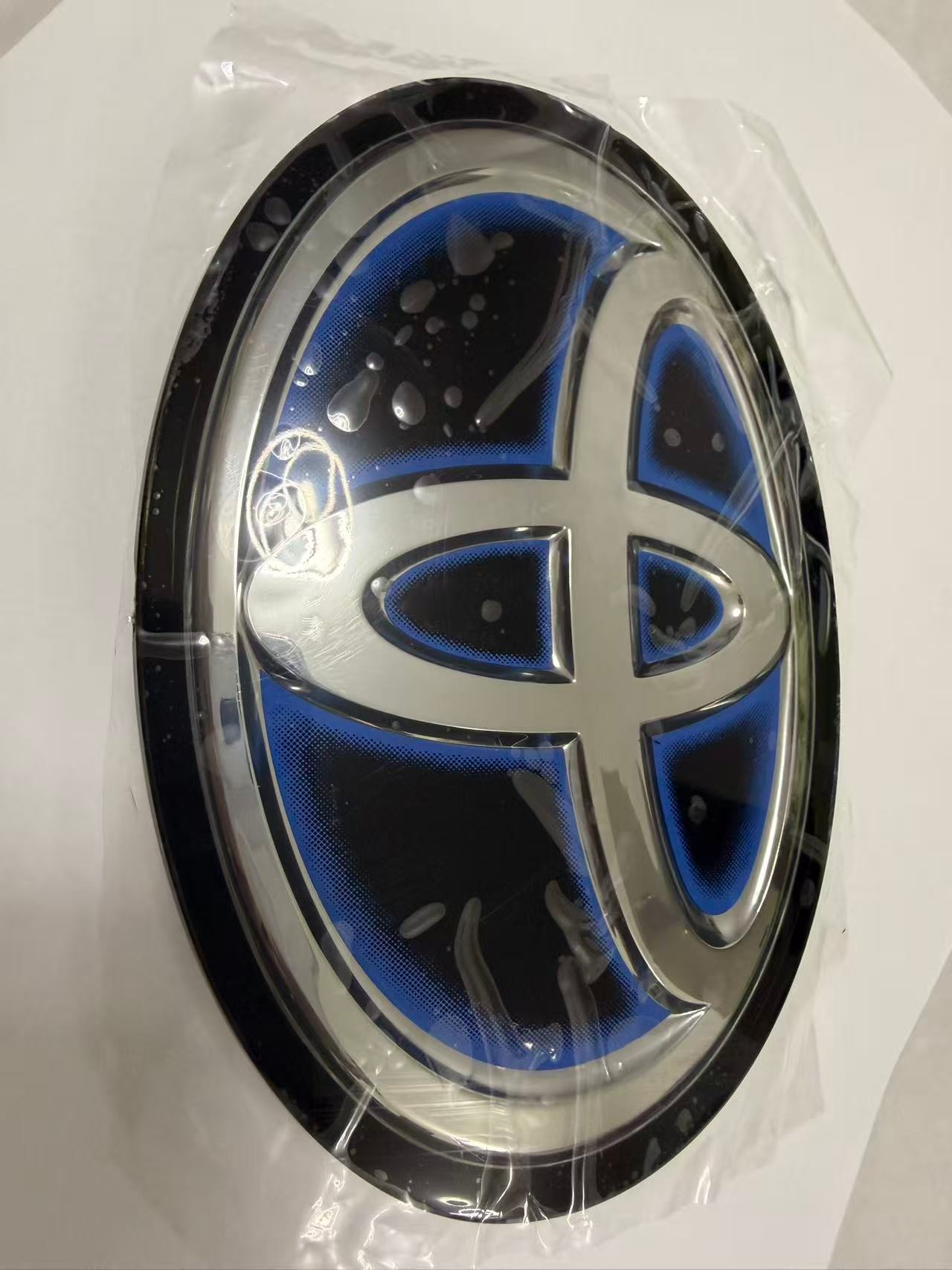 Toyota blue-accent front grille emblem front view, approximately 16 x 11.5 cm